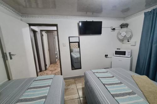 a bedroom with a bed and a tv on the wall at Maluti Backpackers in Phuthaditjhaba