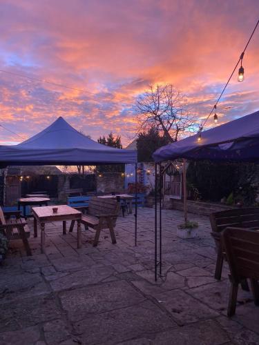 a patio with picnic tables and umbrellas at sunset at The Ilchester Arms Hotel, Ilchester Somerset in Ilchester