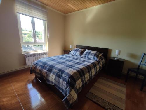 a bedroom with a bed with a plaid blanket and a window at Casa Rural La Rasilla in Castillo-Pedroso