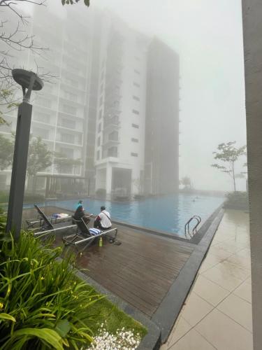 two people sitting on benches near a pool in the fog at Kaw Supreme Theme WIFI Luxury 7 PAX Genting Pool & Mountain View Cuti Genting Homestay Midhills in Genting Highlands