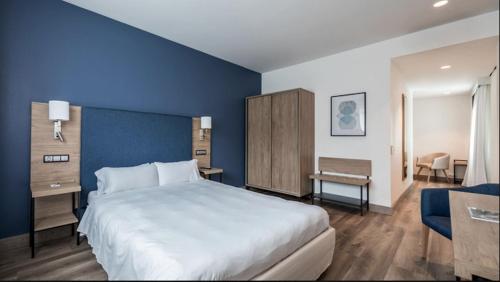 a bedroom with a large bed and a blue wall at Hotel Puerta de Bilbao in Barakaldo