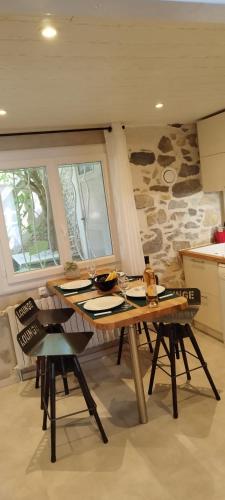 una mesa y sillas en una cocina con una pared de piedra en LE COSY Joli F2 proche gare, Arénes avec terrasse privée en Nimes