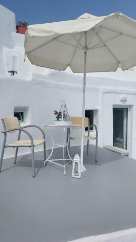a table and chairs with an umbrella in a room at Olympic Villas in Oia