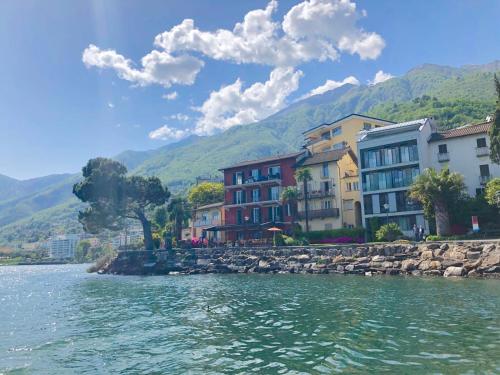a group of buildings next to a body of water at Brissago Lake Apartment in Brissago