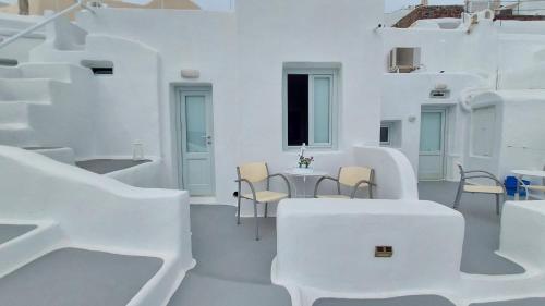 a white room with chairs and a table and stairs at Olympic Villas in Oia