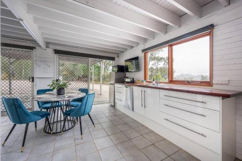 a kitchen with a table and blue chairs at The Riverstone Luxury Eco Home in the Hills in Mudgee
