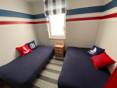 two beds in a room with red and blue stripes at Apartament szafirowy z basenem koło Łeby in Żarnowska