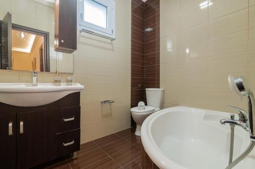 a bathroom with a sink and a tub and a toilet at Taso's Modern House! in Zakynthos Town