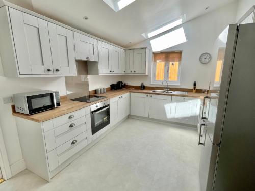 cocina con armarios blancos, fregadero y microondas en Rye Court Cottage - Stunning cottage in central Helmsley with parking en Helmsley