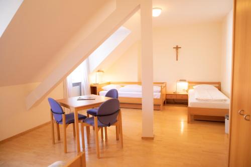 a room with a table and chairs and a bed at Haus der Begegnung Heilig Geist in Burghausen