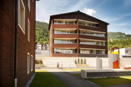 a building with people walking in front of it at Reka-Feriendorf Blatten-Belalp in Blatten bei Naters