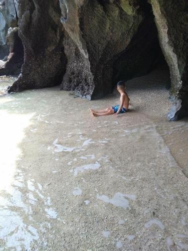 a young boy sitting on the sand at the beach at Mountain Pearl Hotel in Cat Ba