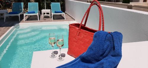 a pool with two glasses of wine and a purse at The Central Villa - Kassiopi Corfu Villas in Kassiopi