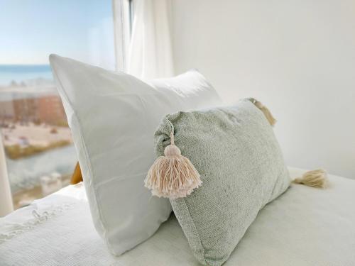 a pillow with a tassel on it sitting on a bed at Global Properties, Apartamento con vistas al mar, Canet d'en Berenguer in Canet de Berenguer