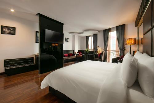 a bedroom with a large white bed and a living room at La Nueva Boutique Hotel Hanoi & Spa in Hanoi