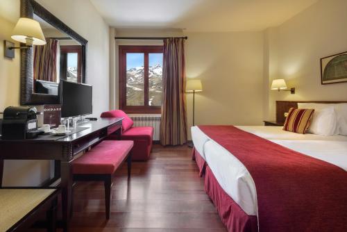 a hotel room with two beds and a desk at Hotel Saliecho in Formigal