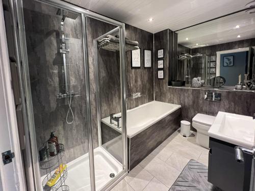 a bathroom with a shower and a tub and a sink at Loch Lomond Mews in Balloch