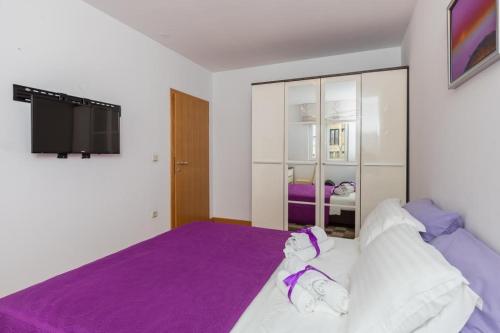 a bedroom with a purple bed and a tv at Apartment Buby in Dubrovnik