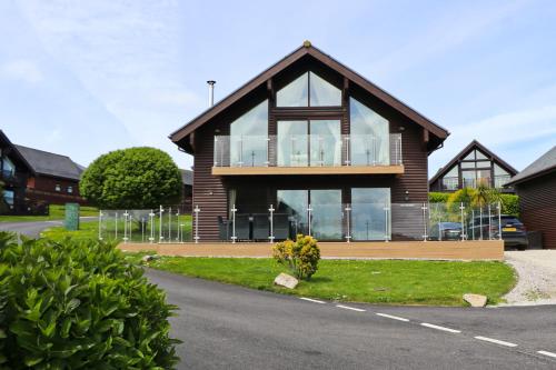 a house with large windows on the side of a road at ON-SITE WATERSPORTS family lodge in Saint Columb Major
