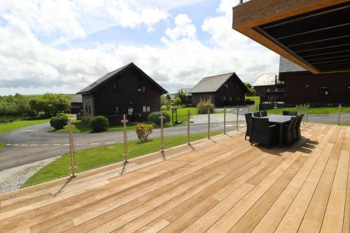 a wooden deck with a table and chairs on it at ON-SITE WATERSPORTS family lodge in Saint Columb Major