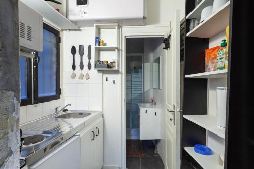 une petite cuisine avec des armoires blanches et un évier dans l'établissement Midoon guest - LA VERRIERE DES TERREAUX - Lyon 1er, à Lyon