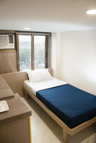 a small room with a bed with a blue blanket at City Hotel in Mumbai
