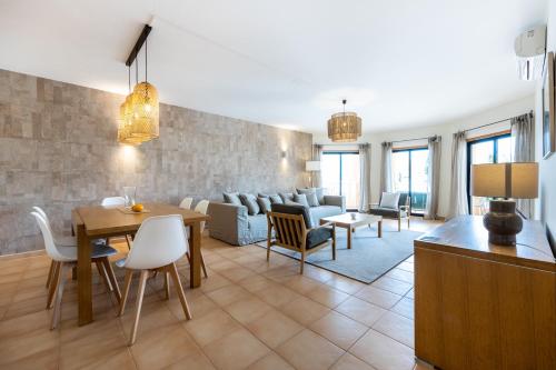 sala de estar con sofá, mesa y sillas en Aum Praia da Luz Resort Apartment, en Luz