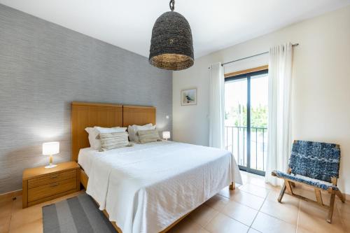 een slaapkamer met een bed en een groot raam bij Aum Praia da Luz Resort Apartment in Luz