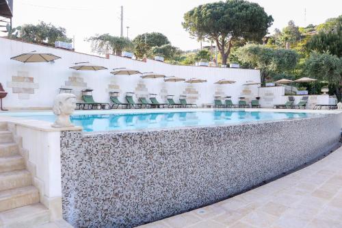 uma piscina com cadeiras e guarda-sóis em Don Vittorio Country Village em Taormina