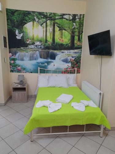 Un dormitorio con una cama verde con una pintura en la pared en SummerAndros Apartment, en Ándros