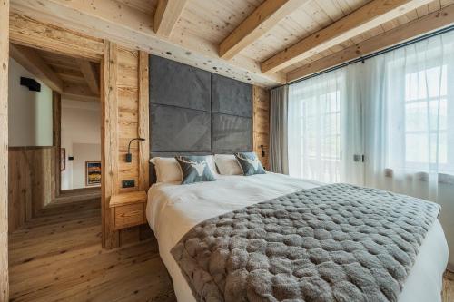 um quarto com uma cama grande e uma janela grande em Chalet Socrepes - Dolomiti Skyline em Cortina dʼAmpezzo