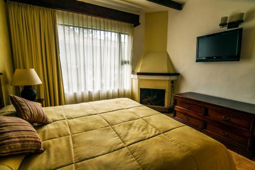 a bedroom with a bed with a fireplace and a television at Hotel Soleil La Antigua in Antigua Guatemala