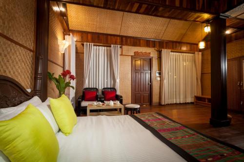 um quarto de hotel com uma cama com almofadas amarelas em Chandara Boutique Hotel em Vientiane