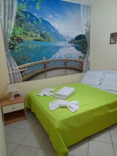 a bedroom with a green bed with a painting of a lake at SummerAndros Apartment in Andros