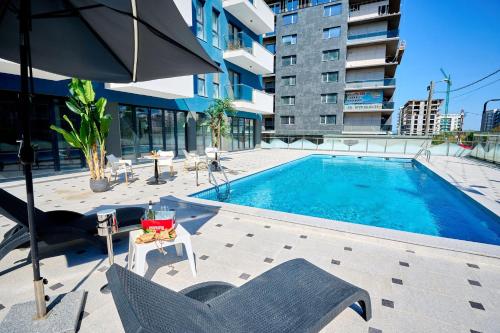 a swimming pool with chairs and an umbrella next to a building at Color Studios in Nord10 - Pool & playground in Mamaia