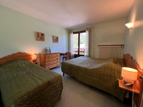 a bedroom with two beds and a table and a window at GROTTE AUX FEES A, appartement skis aux pieds in La Clusaz