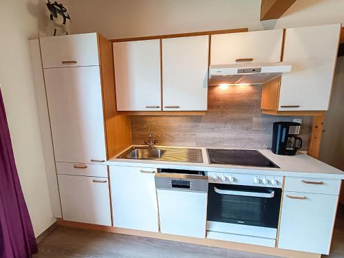une petite cuisine avec des armoires blanches et un évier dans l'établissement Apartment Erna by Interhome, à Kappl