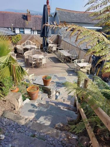 a patio with tables and chairs and a umbrella at Llandudno apartment, quirky pub with tropical beer garden in Llandudno