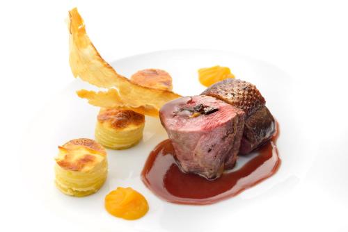 a piece of meat on a plate with caramel and orange segments at Hotel Saliecho in Formigal