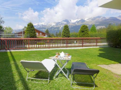 einen Tisch und zwei Stühle in einem Hof mit Bergen in der Unterkunft Studio Valdor by Interhome in Crans-Montana