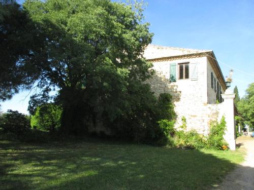 une vieille maison en pierre avec un arbre dans la cour dans l'établissement Mas des Esclots, à Nîmes