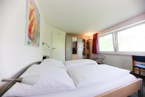 a large white bed in a room with a window at Hotel Albblick Bad Boll in Bad Boll