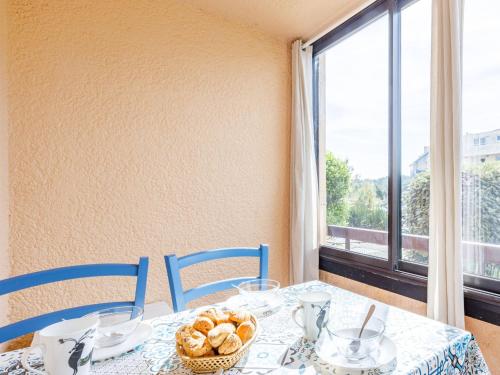 - une table avec des chaises bleues et une assiette de pain dans l'établissement Apartment Les Maisons de l'Océan-7 by Interhome, à Lacanau-Océan