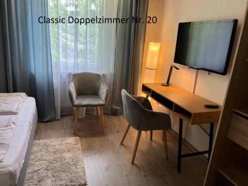 a bedroom with a desk and a television and a bed at HoteLPension am Thermalbad in Bad Nenndorf