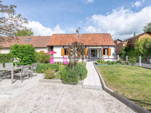 a house with a table and chairs in a yard at Holiday Home La Mesnièroise by Interhome in Mesnières-en-Bray