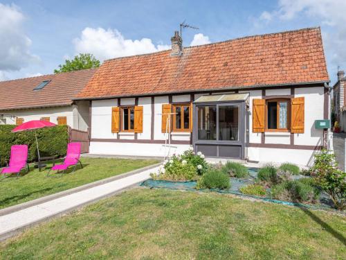 a white house with pink chairs in the yard at Holiday Home La Mesnièroise by Interhome in Mesnières-en-Bray