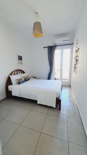 a white bedroom with a bed and a large window at 80 Steps - Beach Apartment in Hanioti