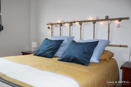 uma cama grande com almofadas azuis em cima em Apartamento Nansa - Casas de los Picos em Celis
