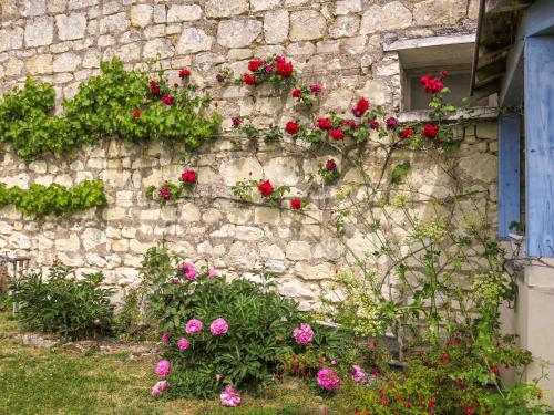 un mur en pierre avec des fleurs qui y poussent dans l'établissement Holiday Home Gîte Le Landhuismes by Interhome, à Huismes
