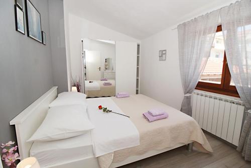 a white bedroom with a bed and a mirror at Vila Anda in Zadar